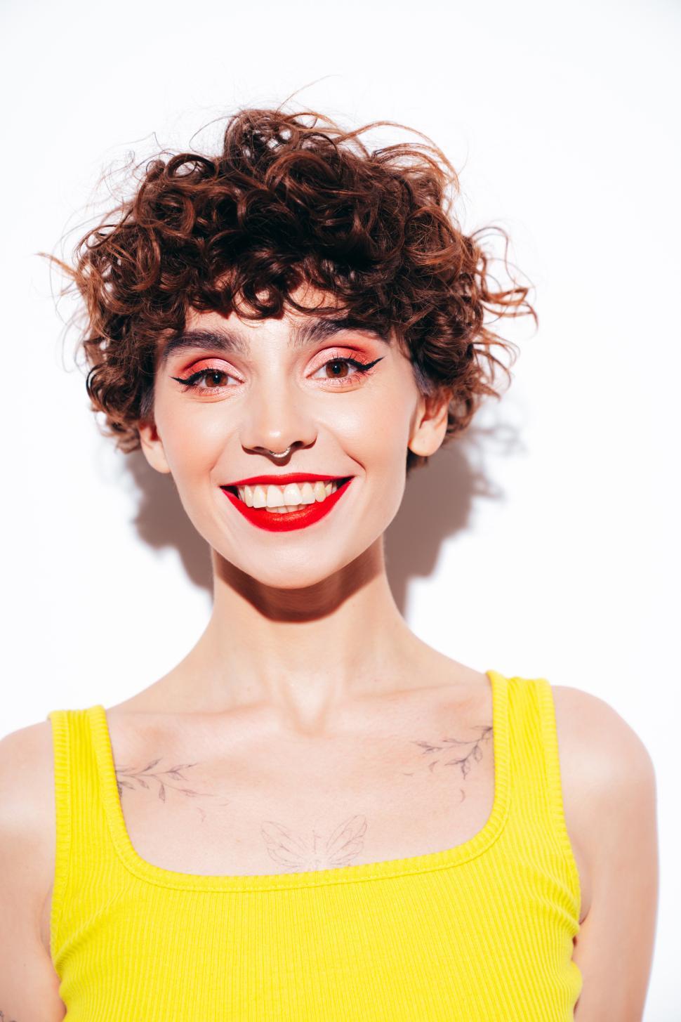 Free Image of Smiling woman with curly hair in yellow tank top 