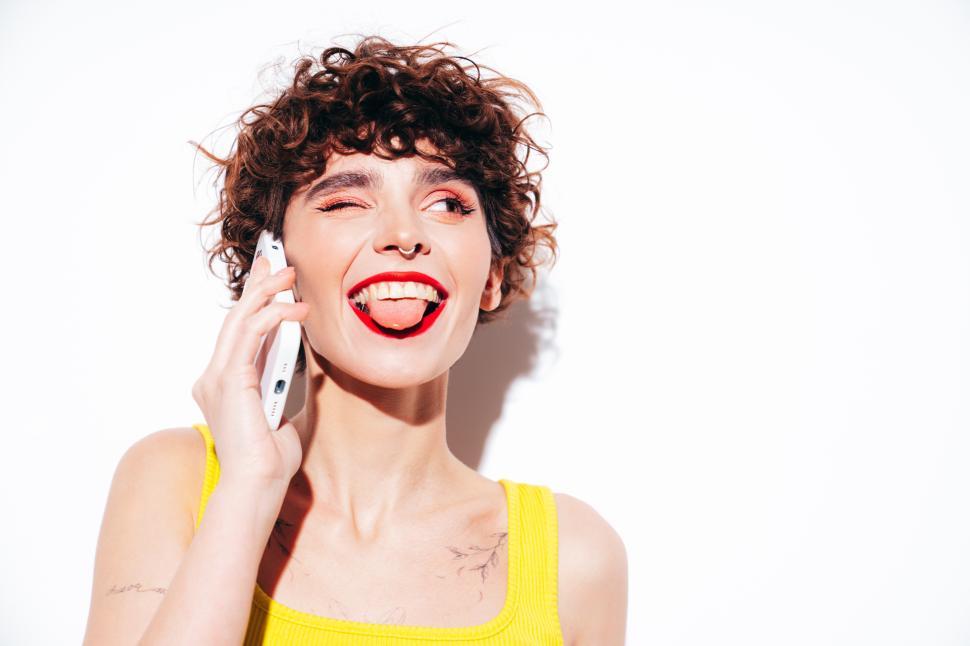 Free Image of Woman in yellow tank top using phone playfully 