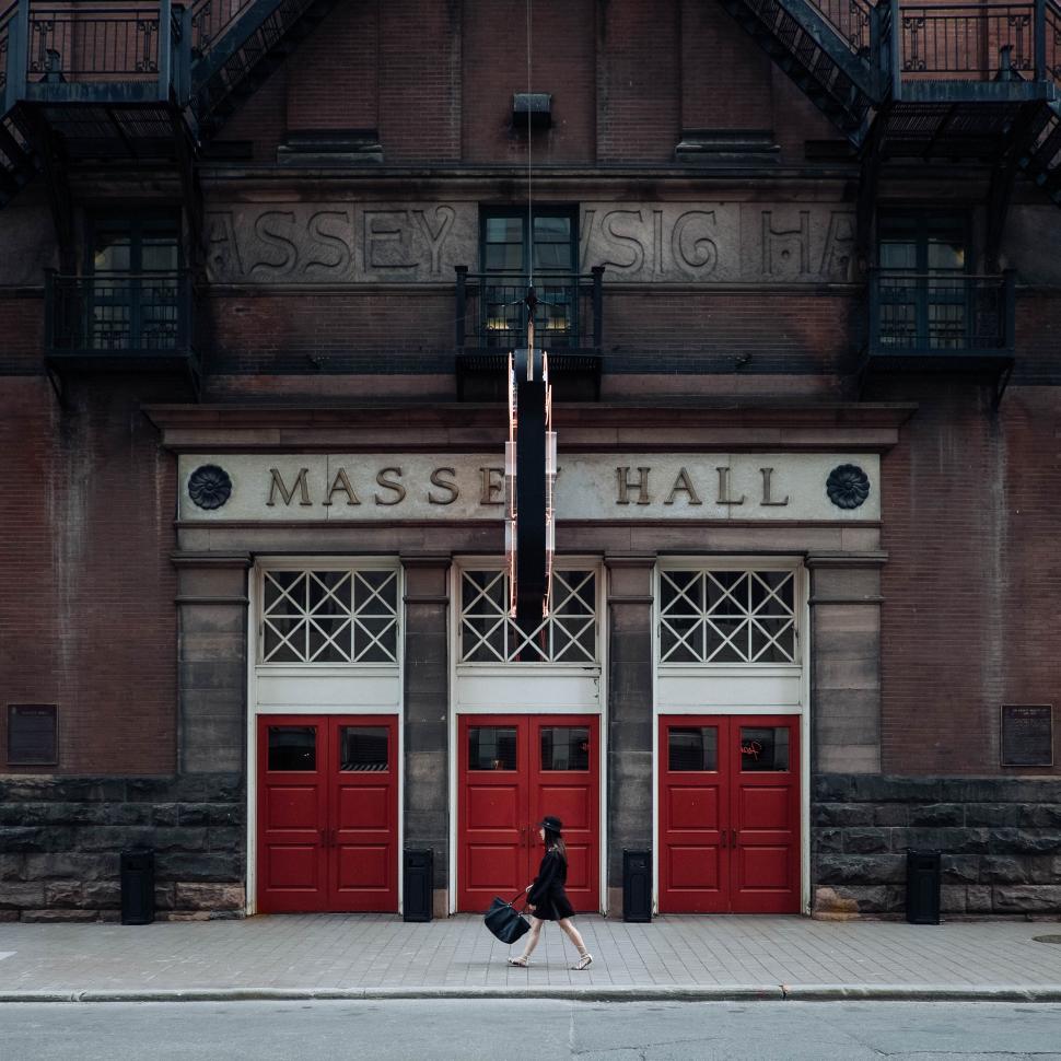 Free Image of Massey Hall with red doors and person walking by. 