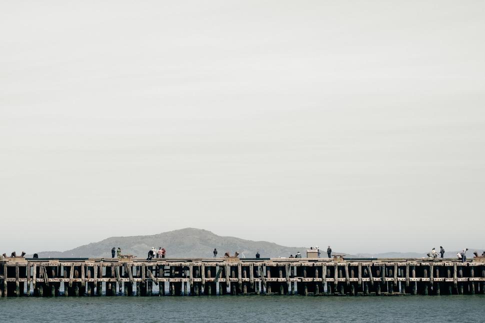 Free Image of People on a pier with mountain in the background. 