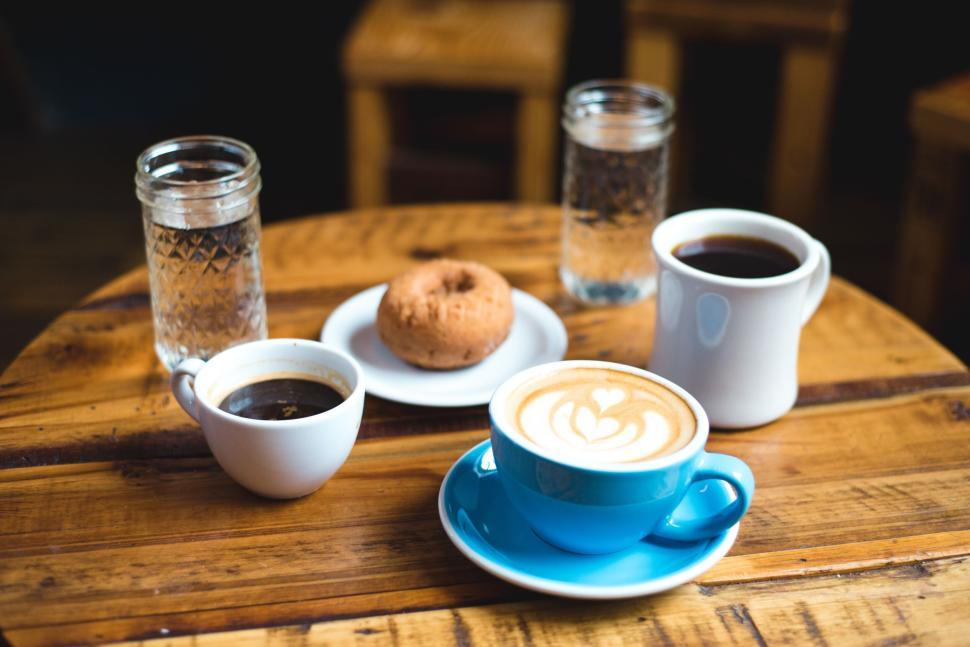 Free Image of Coffee and donut on wooden table, cozy coffee shop 