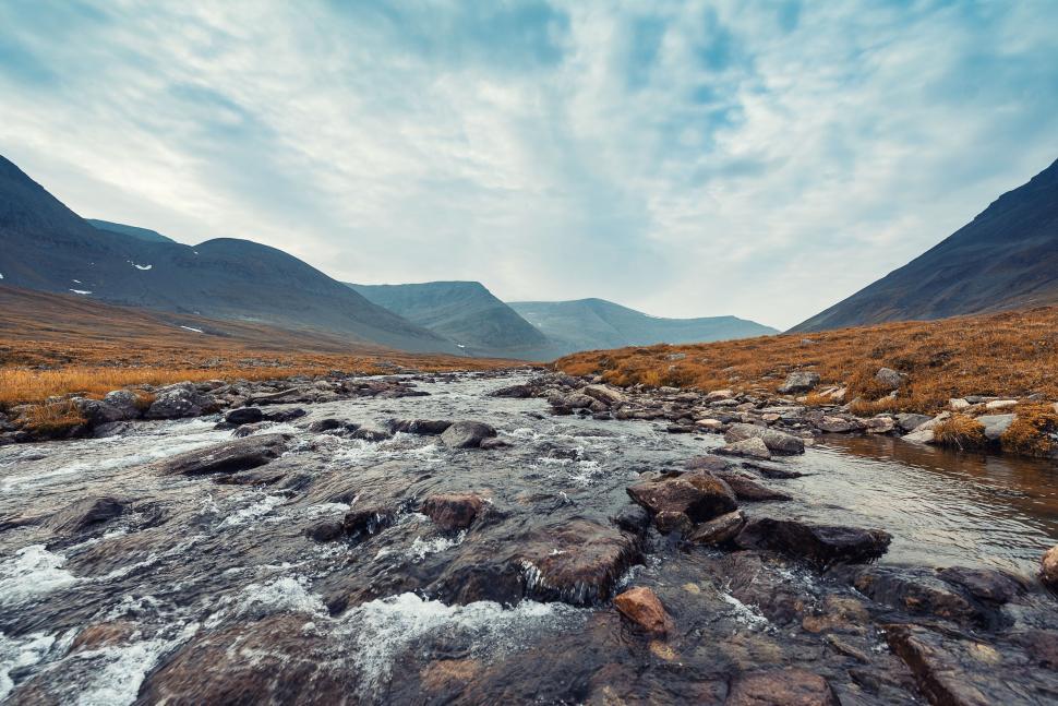 Free Image of Mountain river flowing through rocky landscape under sky 