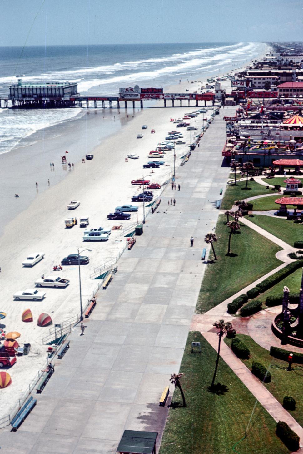 Free Image of Bustling beachfront with cars and pier under sunny sky 