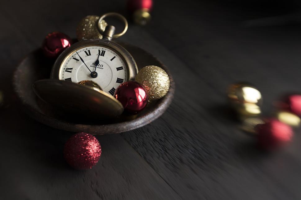 Free Image of Antique pocket watch resting with red and gold baubles. 