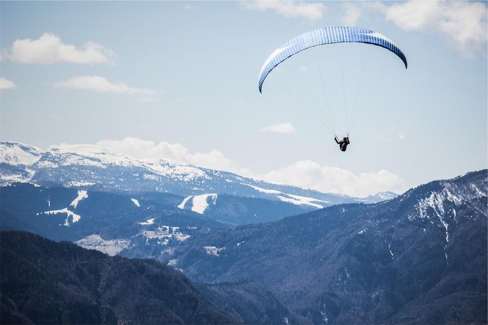 Free Image of Paraglider soaring over snowy mountains in clear sky 