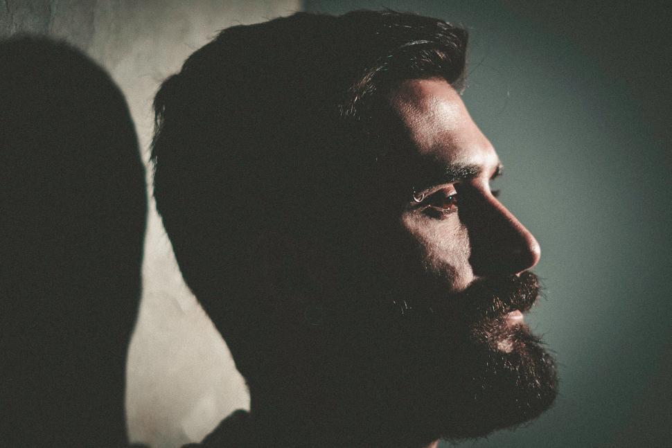 Free Image of Shadowed profile of a bearded man with intense lighting. 