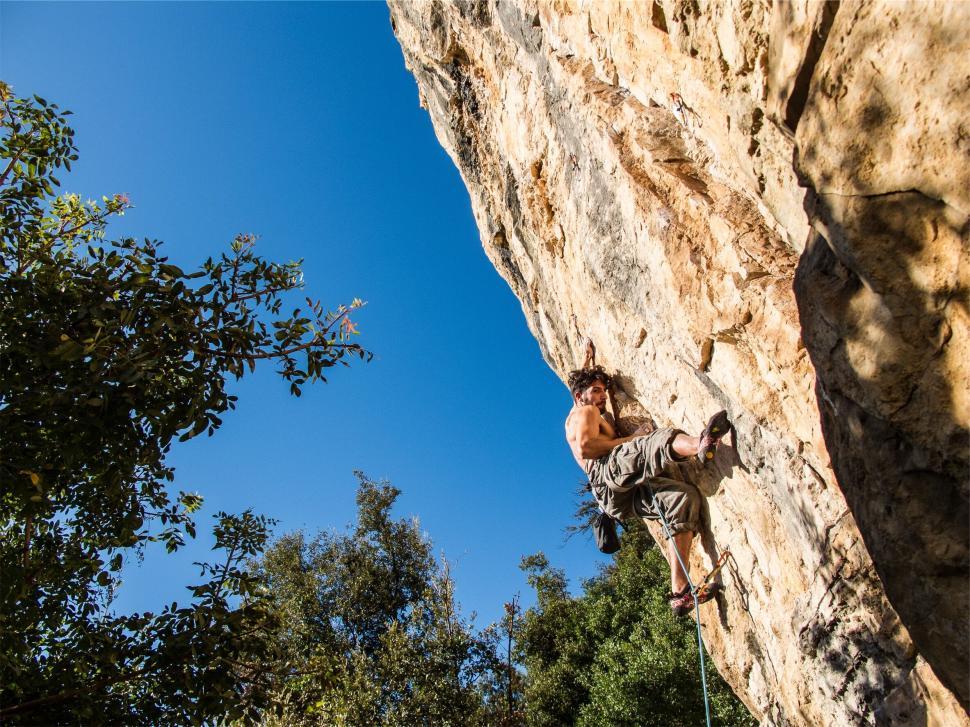 Free Image of Rock climber ascending steep cliff on a sunny day 