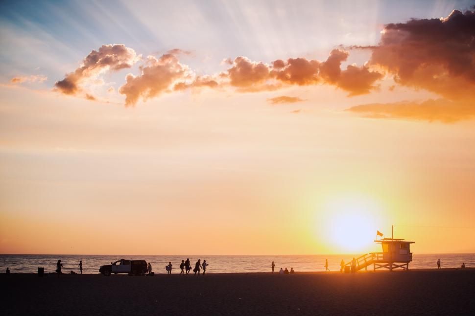 Free Image of Sunset on beach with silhouettes and lifeguard tower 