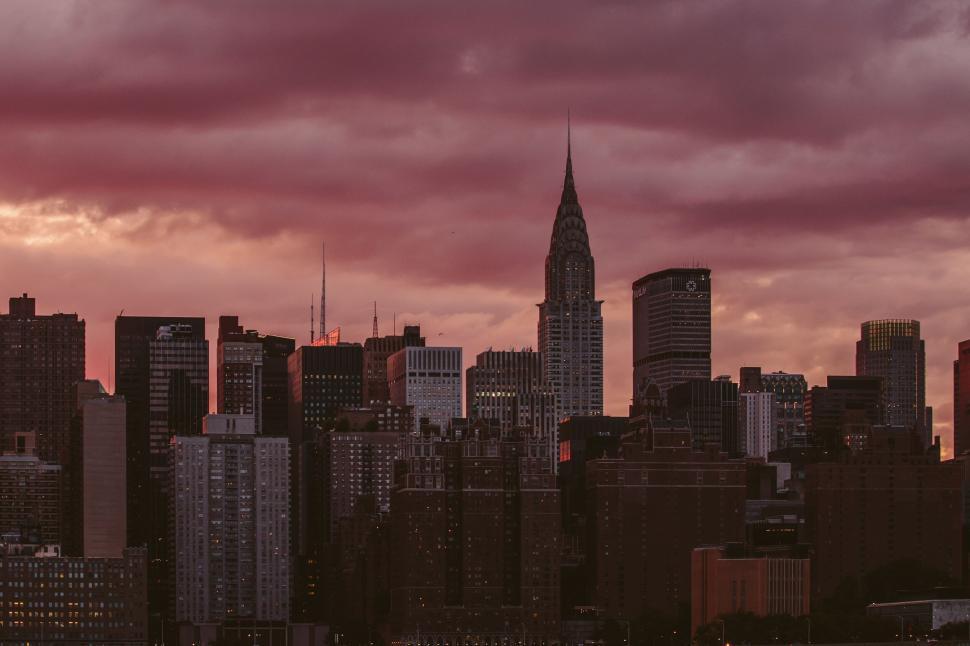 Free Image of City skyline with tall buildings under a pinkish sky. 