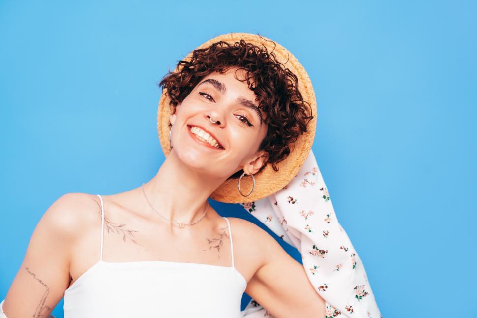 Free Image of Woman smiling with curly hair and tattoos on shoulder. 