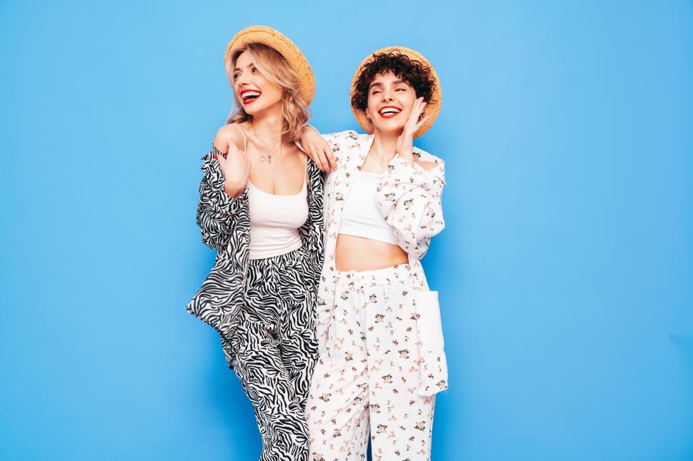 Free Image of Two women smiling together in printed outfits and hats. 