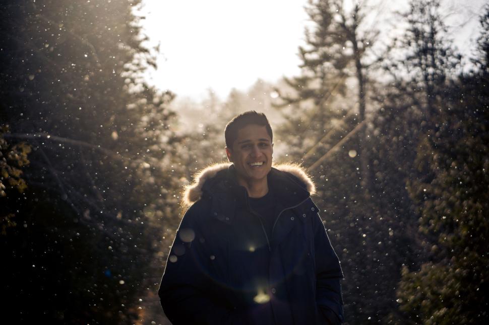 Free Image of Smiling person in a winter coat under falling snowflakes 