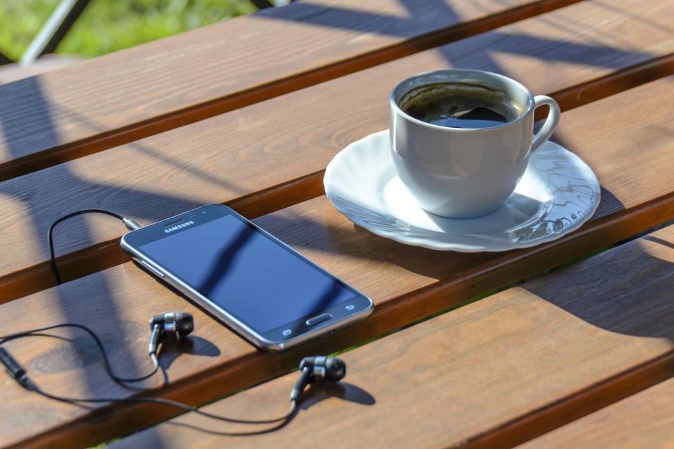 Free Image of Smartphone and coffee cup on wooden table outdoor view 