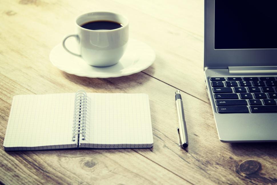 Free Image of Notebook, pen, coffee cup, and laptop on wooden desk 