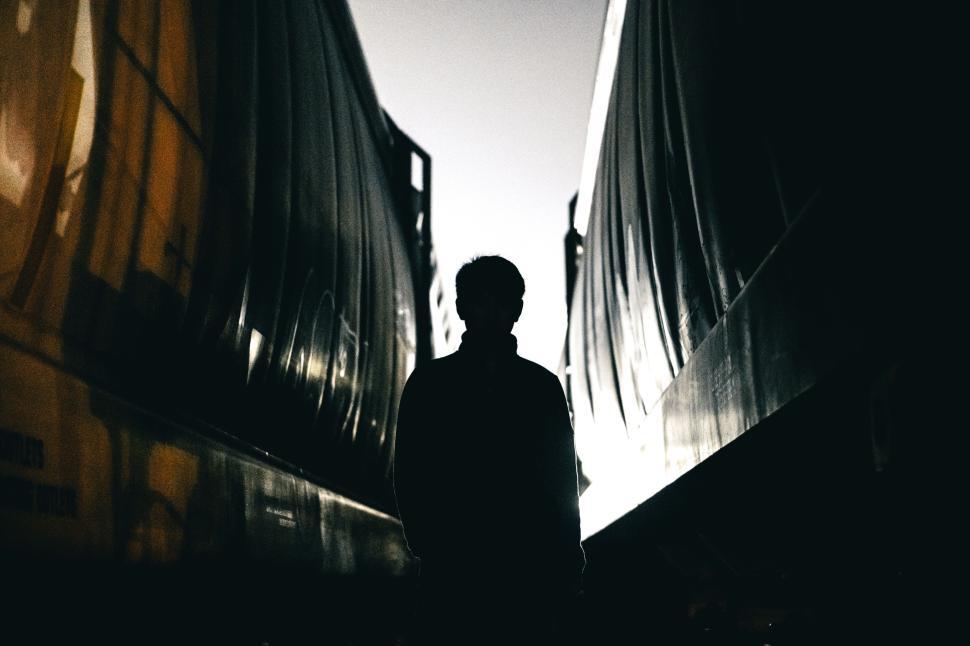 Free Image of Silhouette person standing between two railcarriages. 
