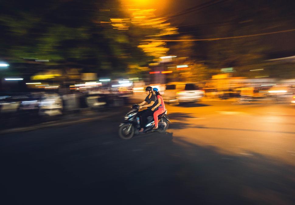 Free Image of People on a motorcycle speeding through city streets at night. 