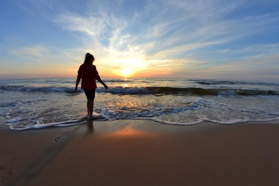 Free Image of Person walks along the shoreline at sunset by the sea. 