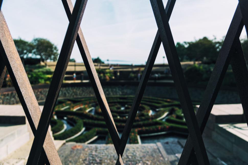 Free Image of Artistic view through iron bars of a landscaped garden. 