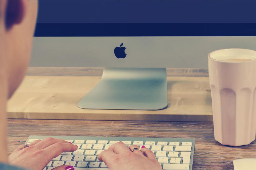 Free Image of Person typing on keyboard with coffee cup on the table. 