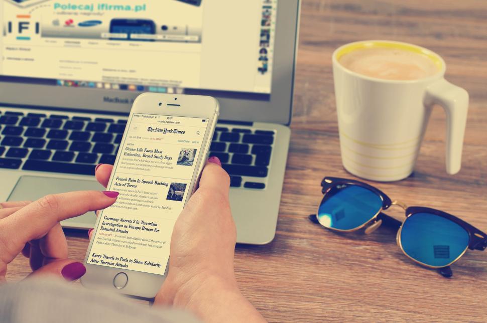Free Image of Browsing news on smartphone with laptop and coffee. 