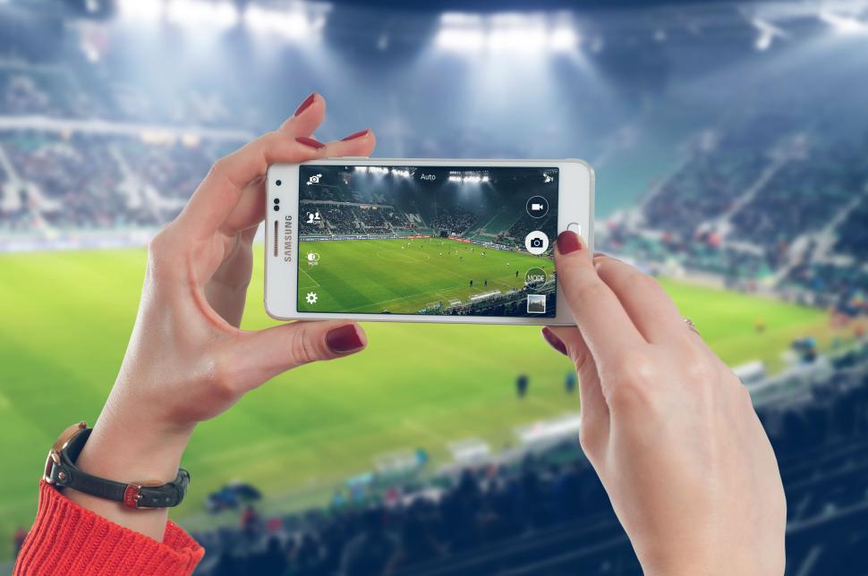 Free Image of Person taking a photo at a stadium during a live event. 