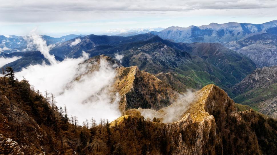 Free Image of Mountain peaks with clouds and green valleys below. 