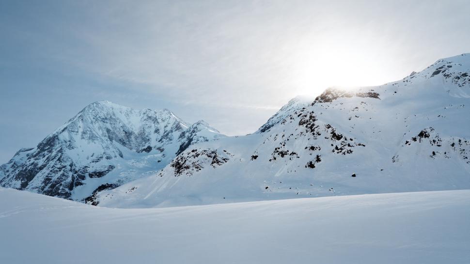 Free Image of Bright sunlight over snowy mountains in clear sky. 