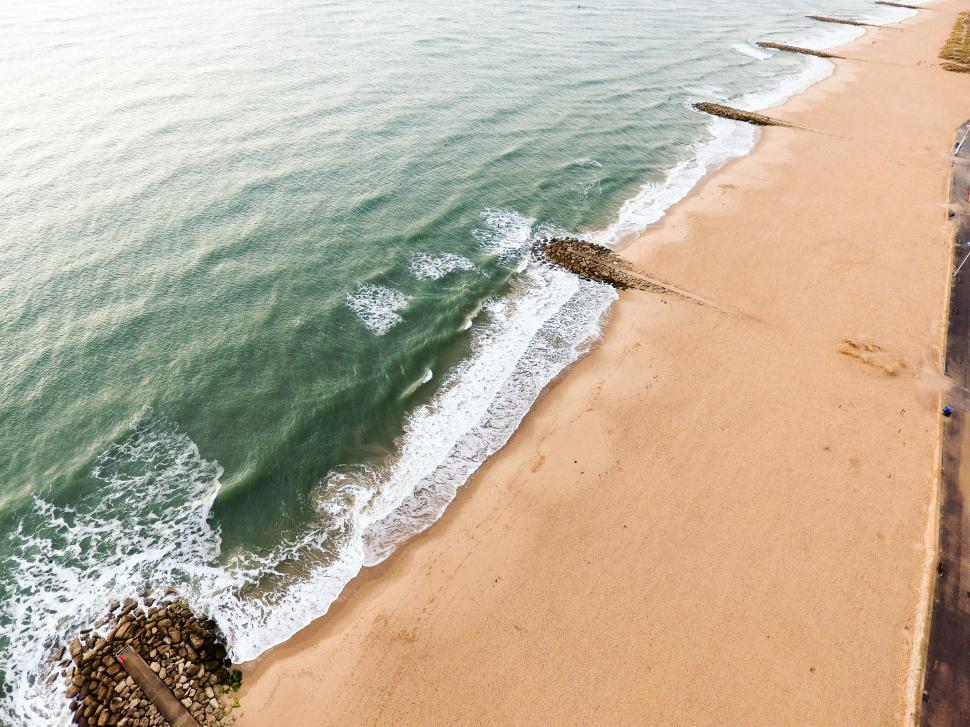 Free Image of Aerial view of a sandy beach with ocean waves. 