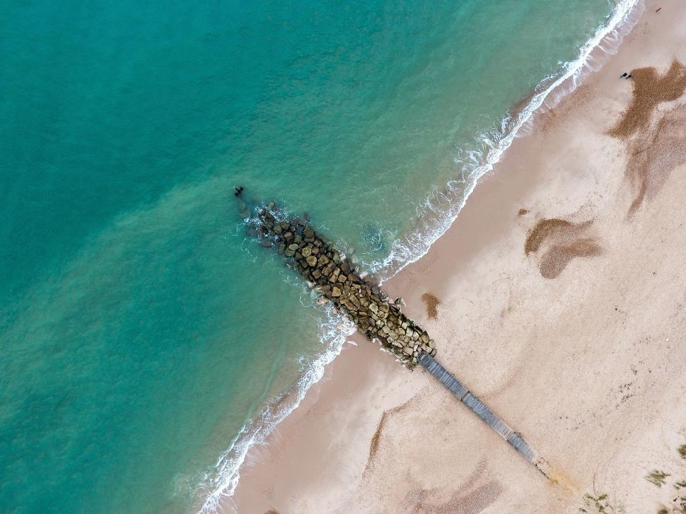 Free Image of Top-down view of a rocky pier extending into the sea. 