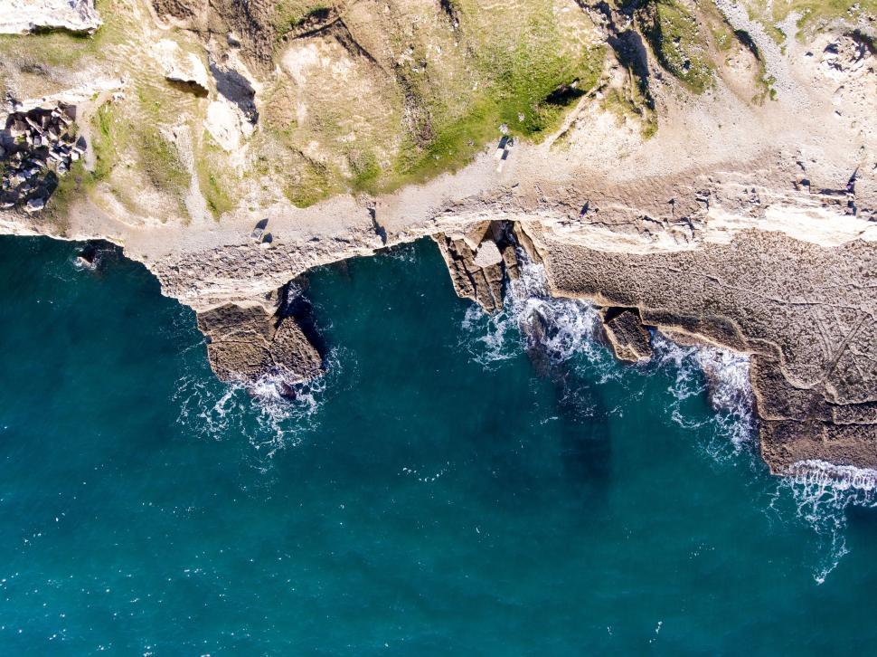 Free Image of Aerial view of rugged coastal cliffs with crashing waves. 