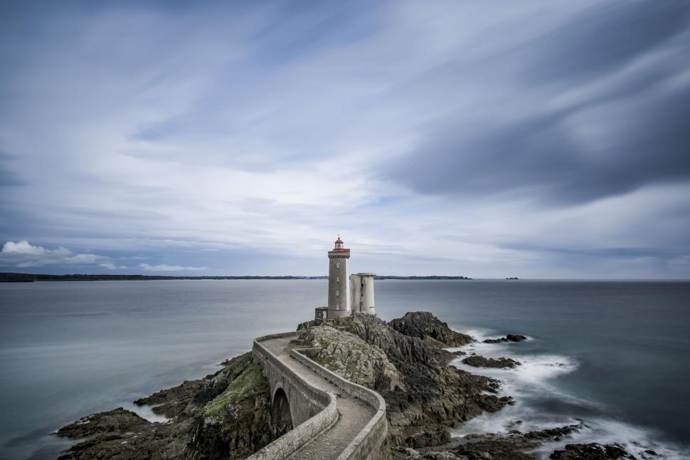 Free Image of Historic Coastal Lighthouse Overlooking Calm Blue Sea 