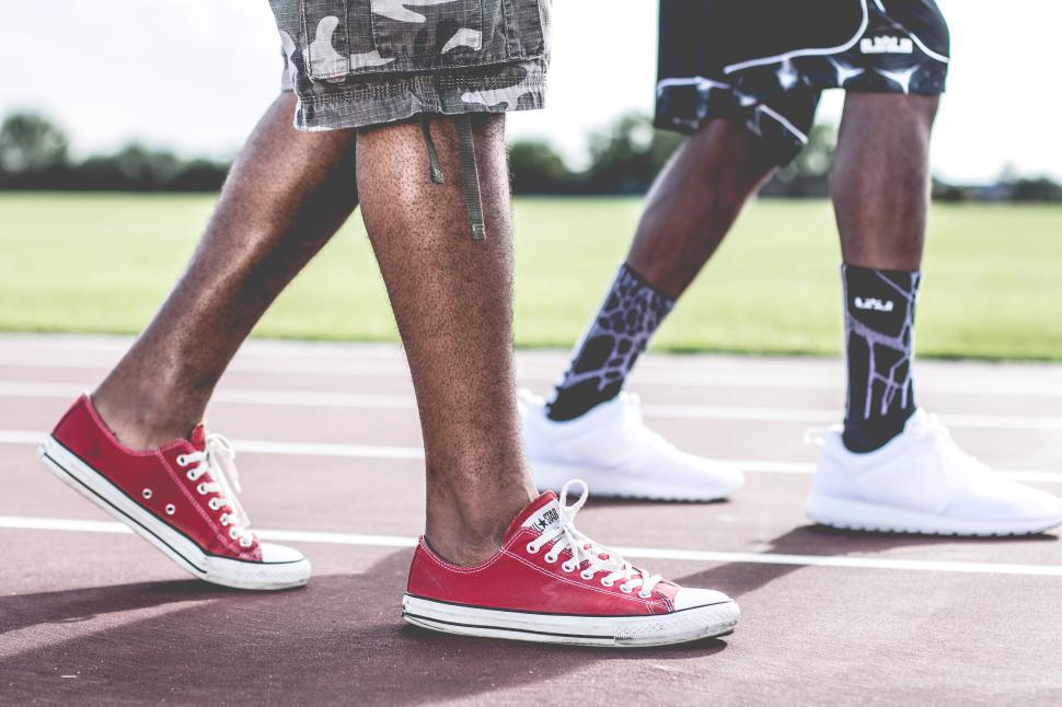Free Image of Two people walking on a track wearing trendy shoes 