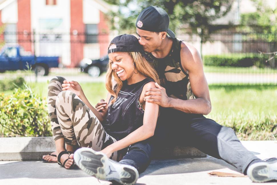 Free Image of Couple sitting on ground, embracing outdoors 