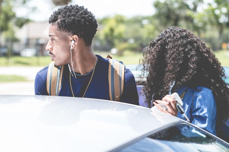 Free Image of Two friends standing beside a car outdoors 