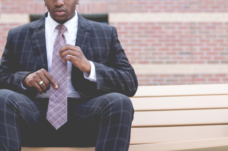Free Image of Man in checkered suit adjusting pink patterned tie 