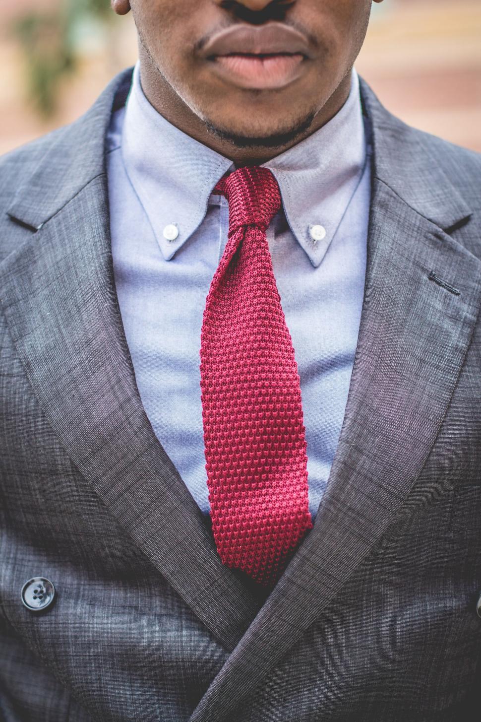 Free Image of Man in a gray suit close-up with red textured tie 