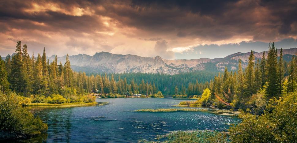 Free Image of Stunning lake nestled among pine trees and mountains 
