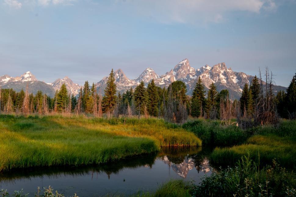 Free Image of Mountain landscape with a grassy field and reflective water. 