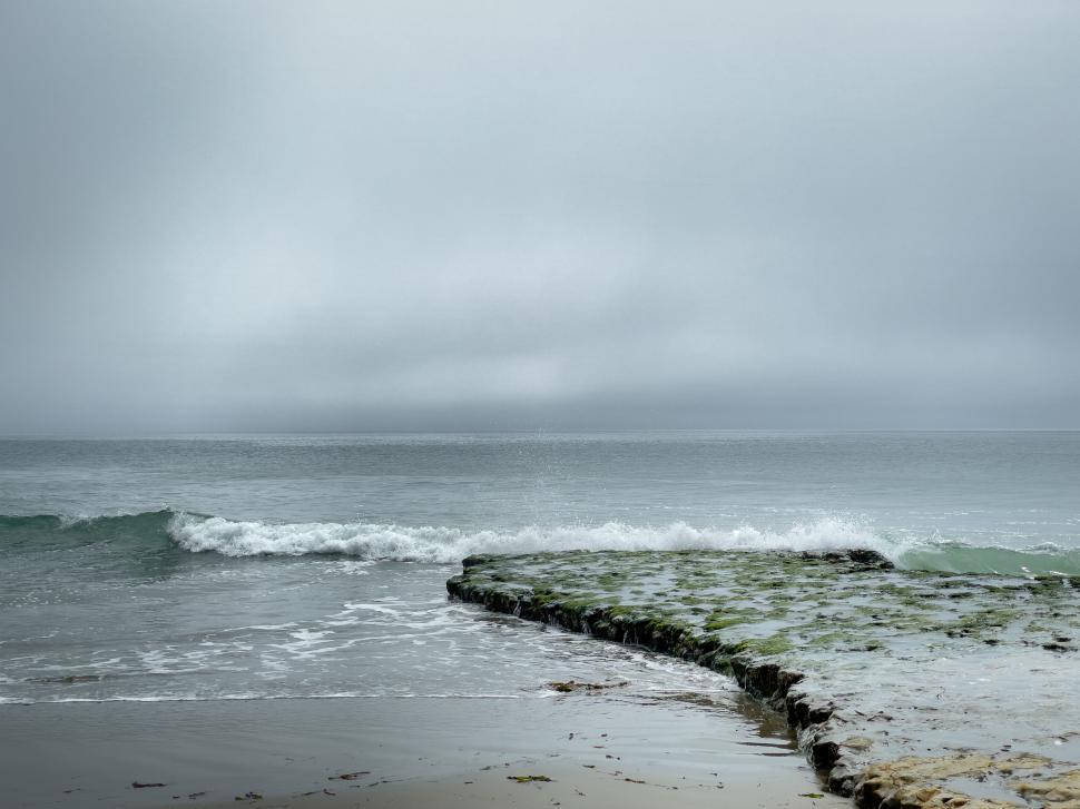 Free Image of Foggy coastline with waves gently hitting the shore 