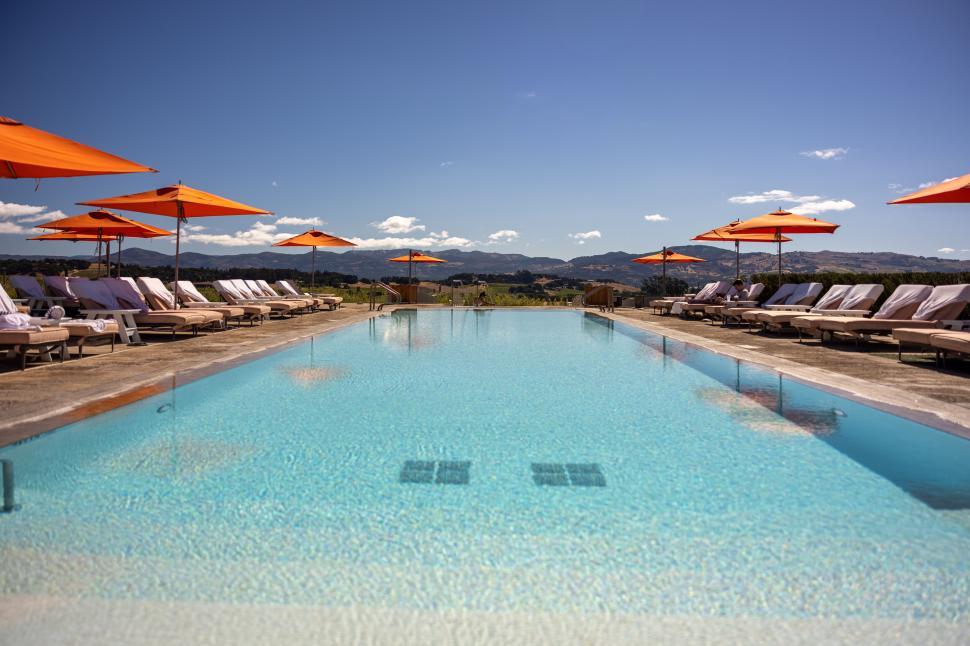 Free Image of Luxury outdoor pool with orange umbrellas and sunbeds 