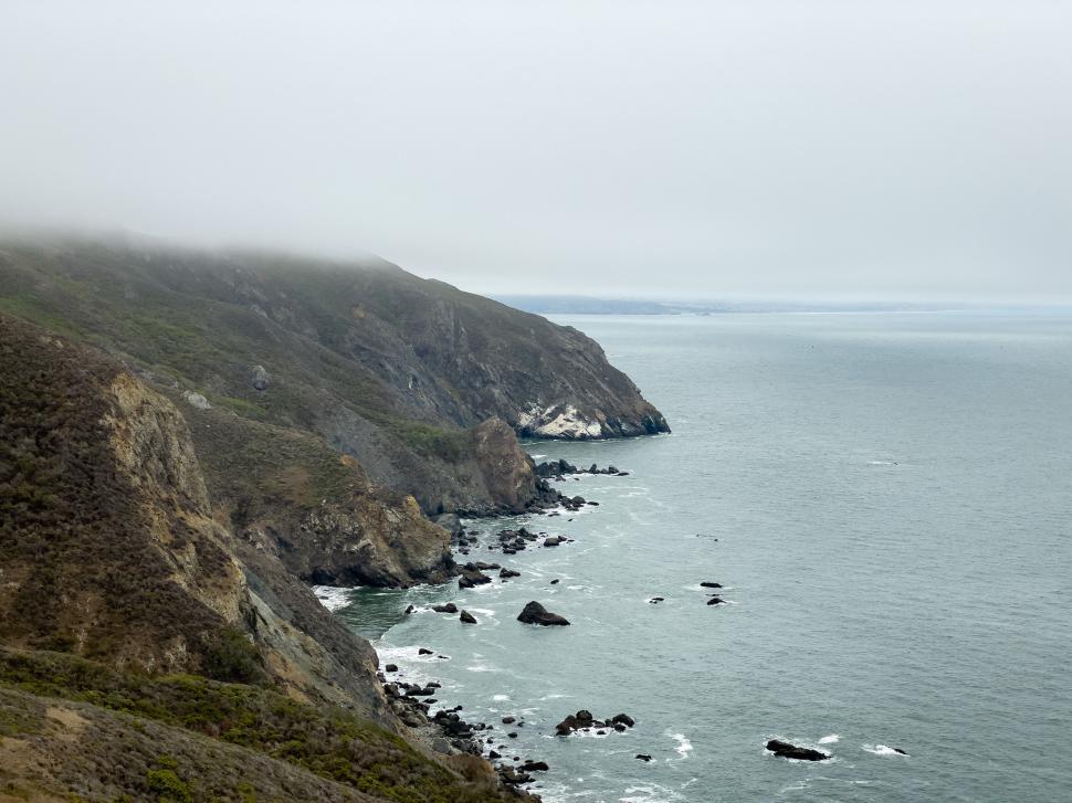 Free Image of Foggy coastline with rocky cliffs and misty horizon view 