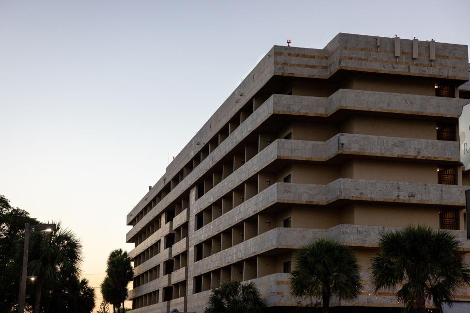 Free Image of Modern multi-story building with palm trees at dusk. 