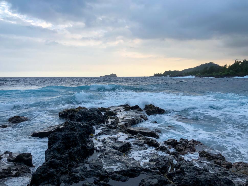 Free Image of Waves crashing on rocky shore at sunset, scenic view 