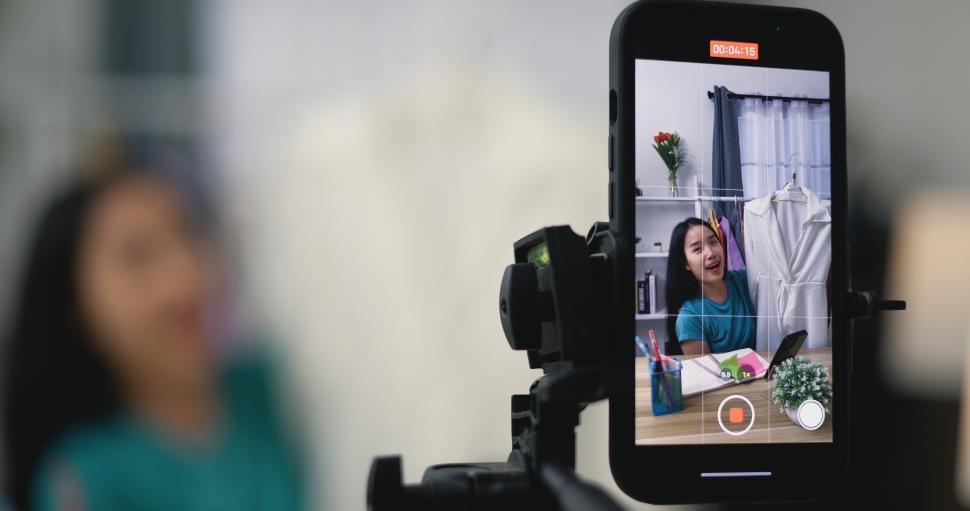 Free Image of Young Asian female fashion designer using mobile phone live steaming 