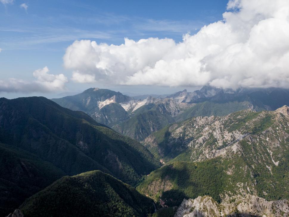 Free Image of Mountain range with clouds under blue sky view. 