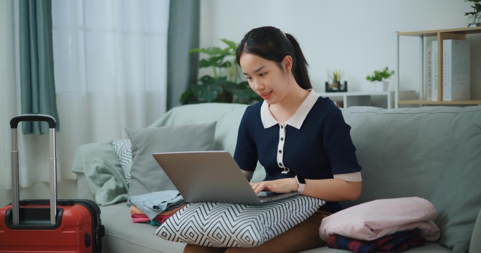 portrait-of-asian-teenager-woman-sitting-on-sofa-using-laptop-for-prepare-booking-hotel-and-airplane-tickets.jpg
