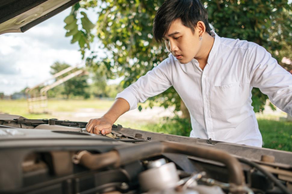 Free Image of Man opens the hood of a car to fix the car. 