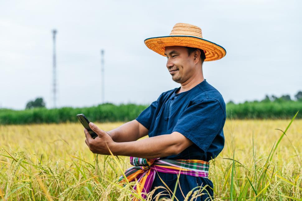 Free Image of Happily young farmer in rice field and use smartphone take a photo 