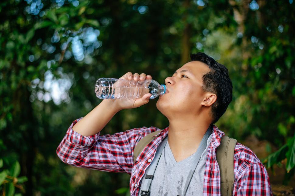 Free Image of Young trekking drink water from bottle during break on trail 