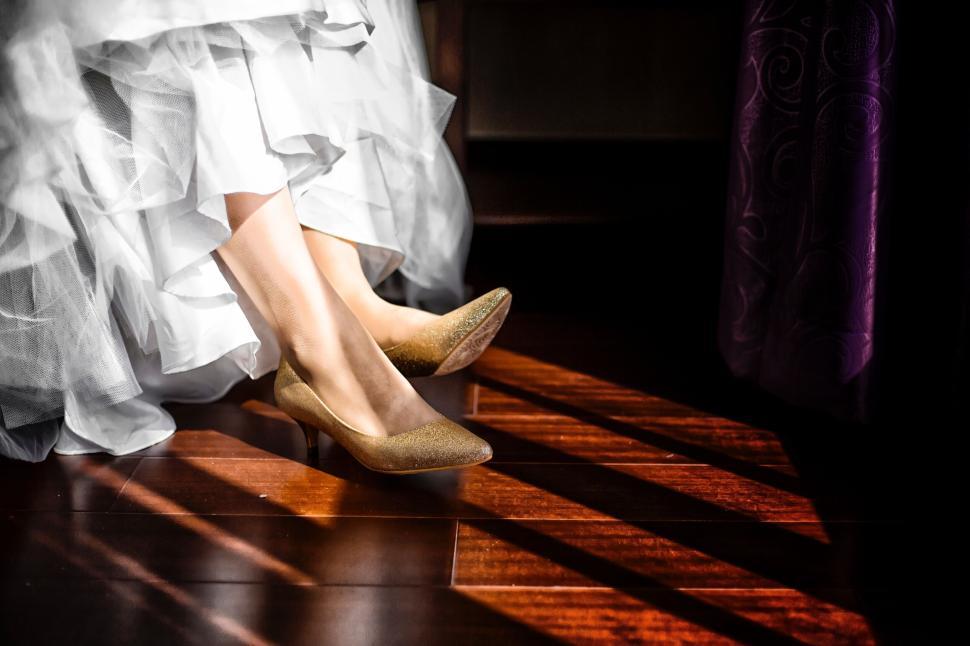 Free Image of Brides legs and golden shoes on wood floor with light. 
